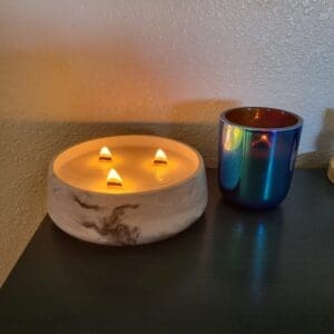 Lit candle and colorful cup on table.