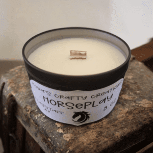 Candle labeled "Horseplay" on rustic surface.