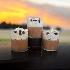 Three chocolate mousse glasses with whipped cream.
